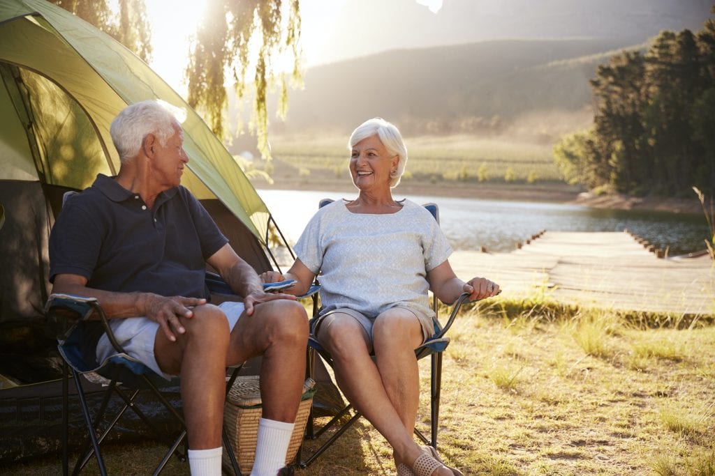 Senior Couple Enjoying Camping Vacation By Lake Together